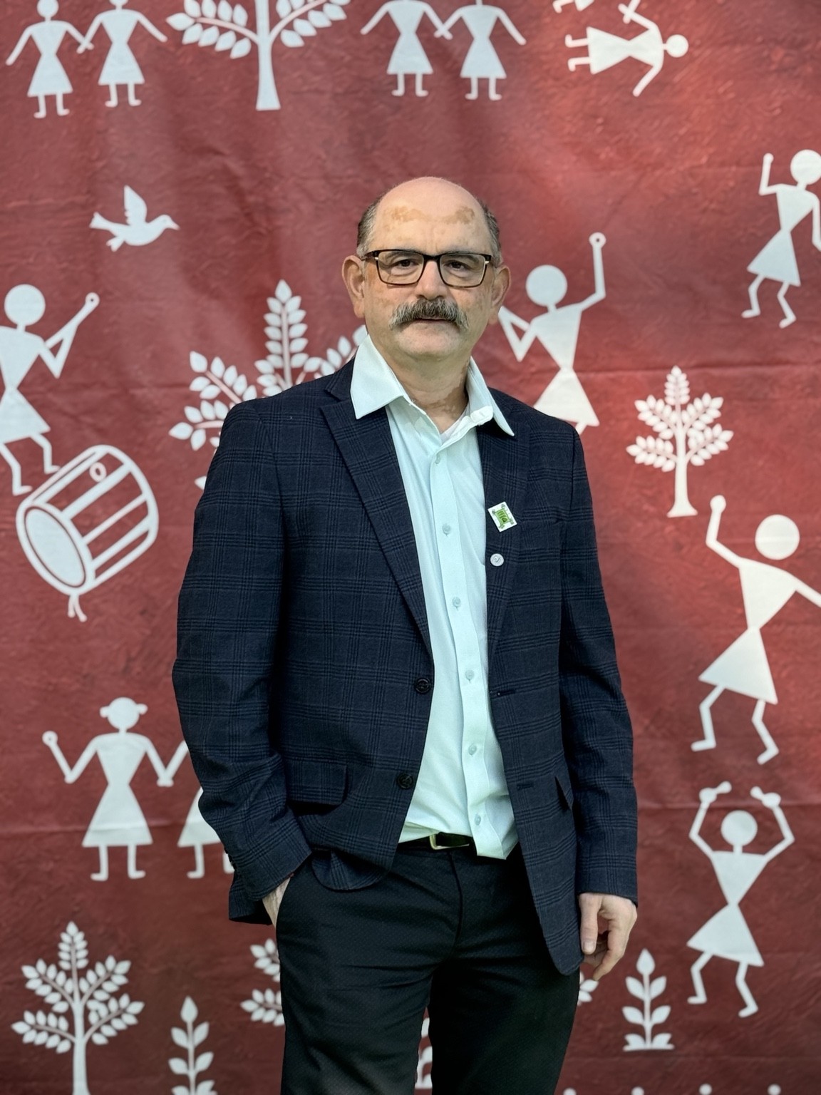 Abhay Dharmadhikari wearing a blazer against a red illustrated backdrop
