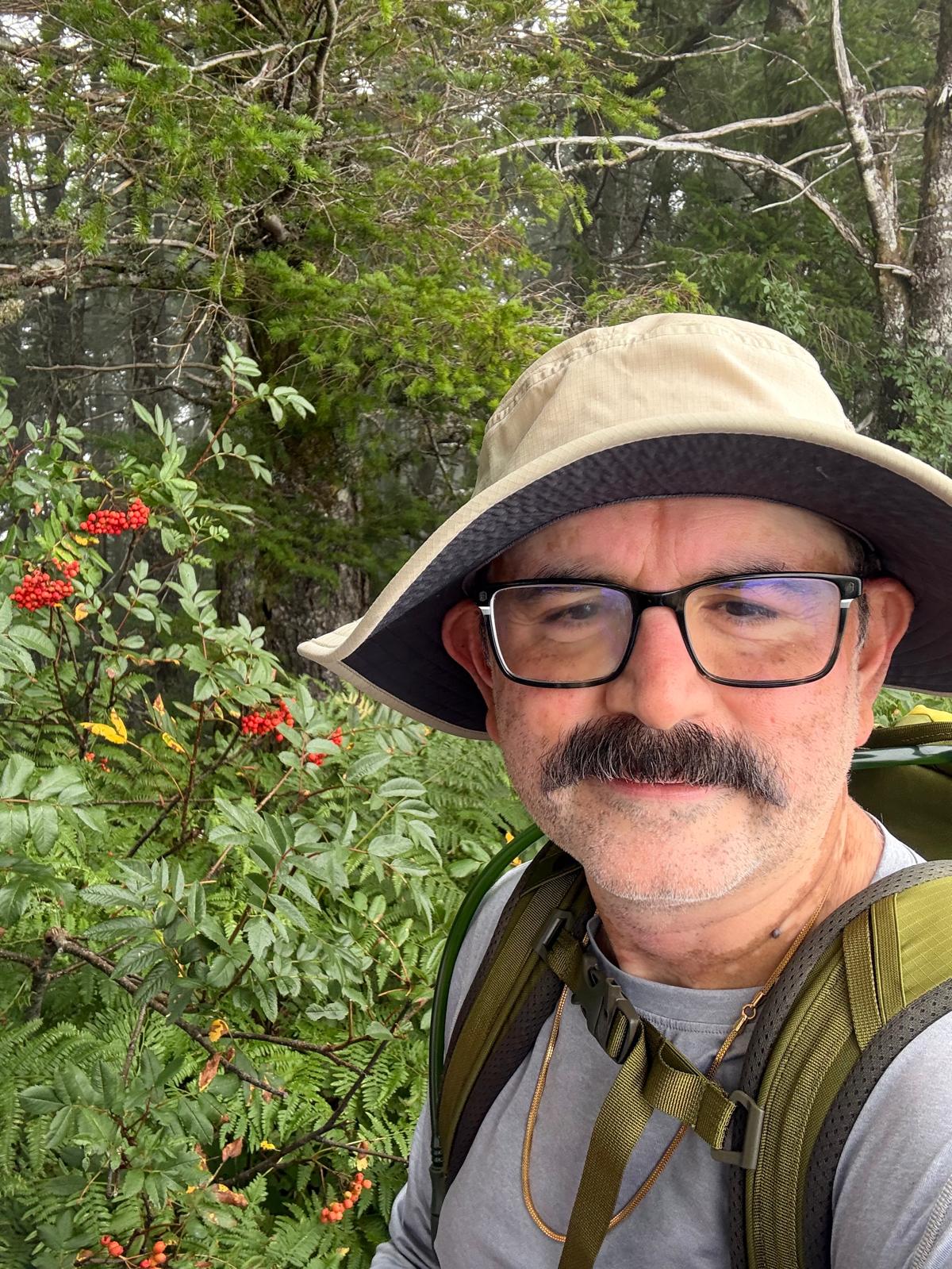 Abhay Dharmadhikari outdoors with a hiking hat and backpack